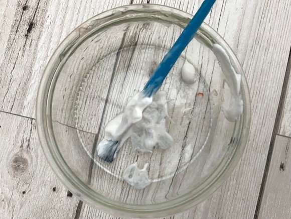 Glue in a small glass jar with a paint brush