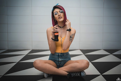 Sexy chica con coca cola en la mano y sentada en un piso blanco