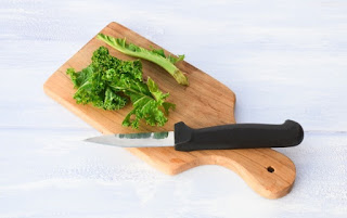chopping woody stalks from kale on wooden board