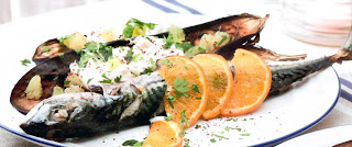 Barbecued mackerel served with baked aubergines and orange garnish.