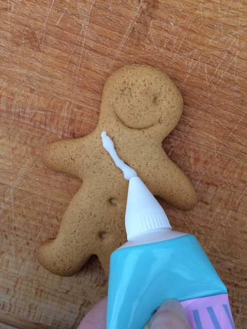 Gingerbread men being decorated with piped icing