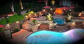 Backyard at night with swimming lit swimmimg pool.