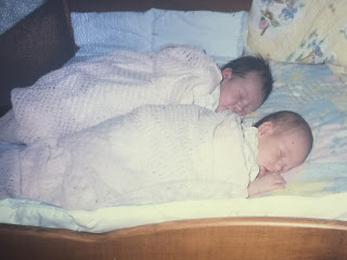 newborn twin baby girls sleeping on a bed