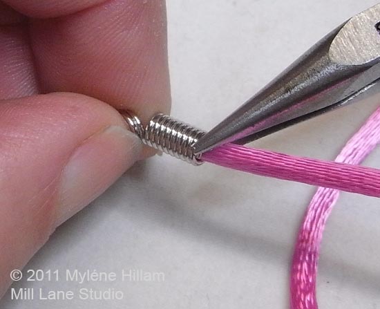 Crimping the last ring of a coil end around rat tail satin cord.