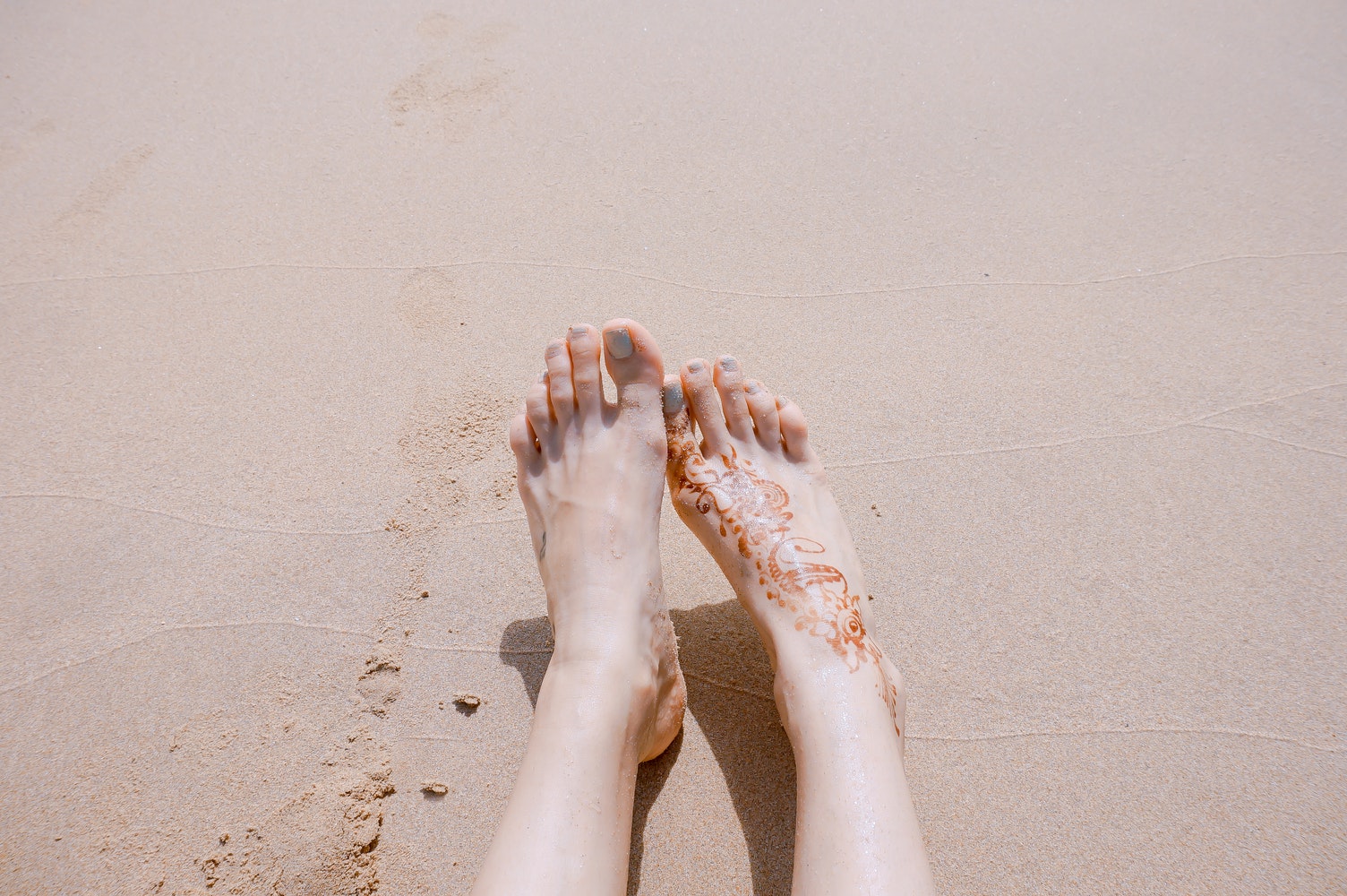 a close-up of two women feet on a sand
