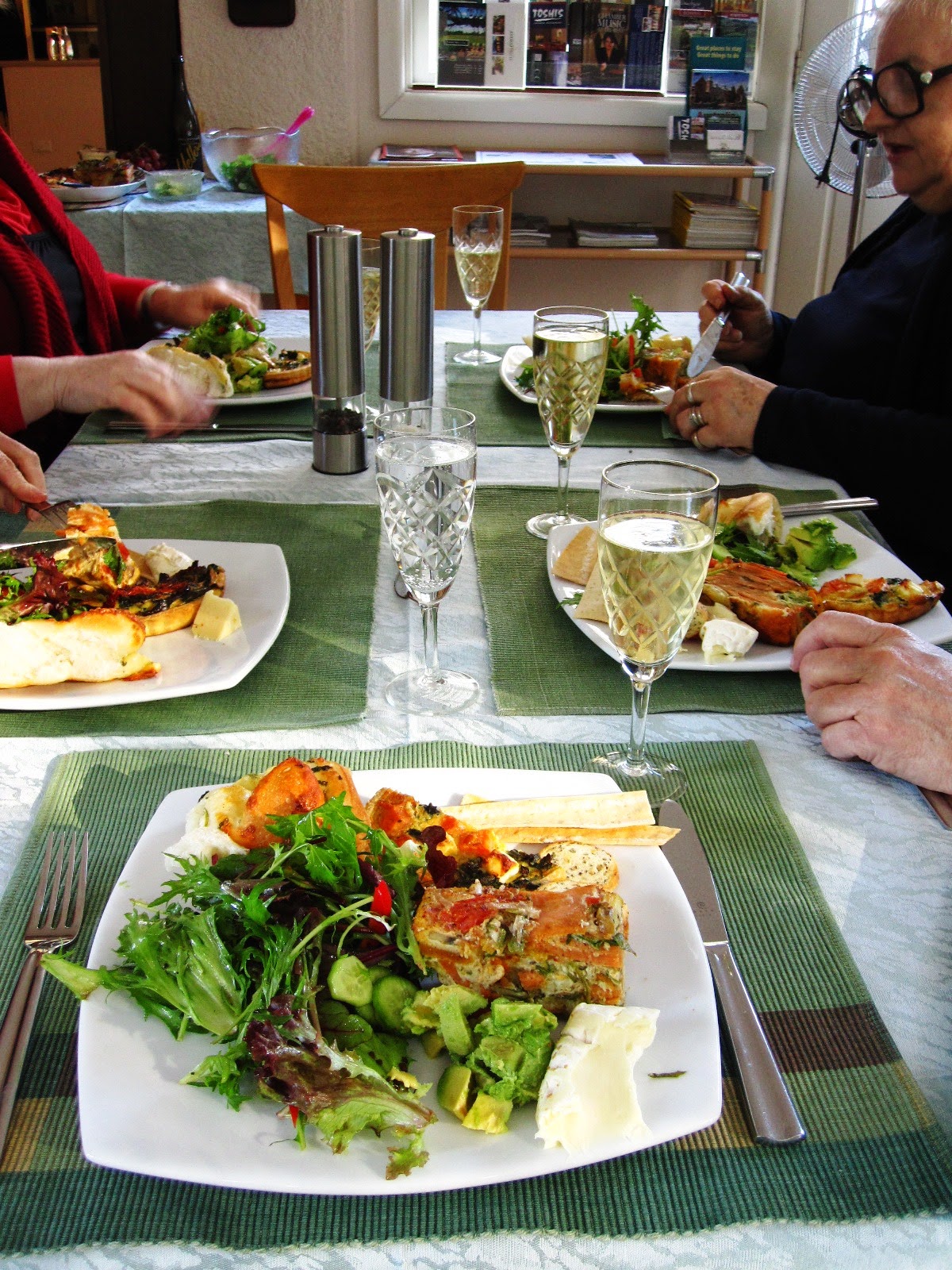 Table with five people eating lunch with glasses of sparkling wine.