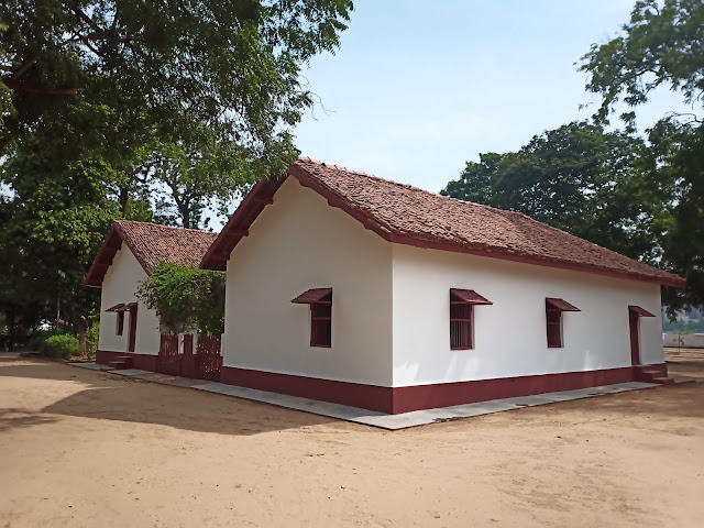 Front of Mahatma Gandhi's white painted house on red foundations with red thatched roof