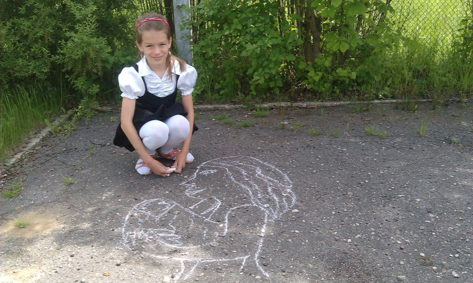Пописала вк. Девочка рисует на асфальте. Асфальт и кусты. Первоклассница на корточках.