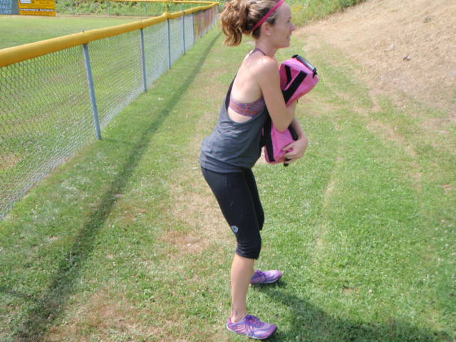 Woman holding the Ultimate Sandbag in front of her chest getting ready to perform a squat