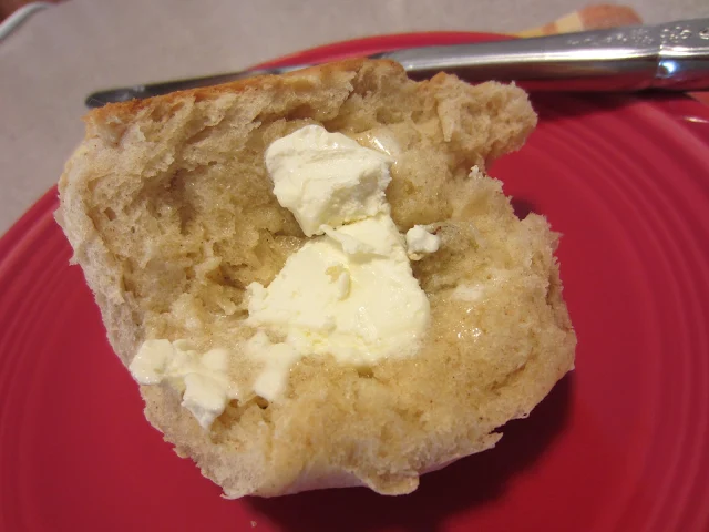 Easy Hot Cross Buns by Renee's Kitchen Adventures on a red plate with a knife split open with butter on it