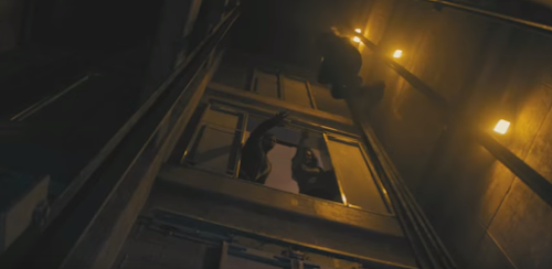 Alicia hanging on elevator cables as two walkers reach for her