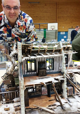 A man looking at a model bombed-out building diorama at a scale model exhibition.