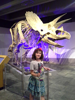 girl with cane in front of a Triceratops