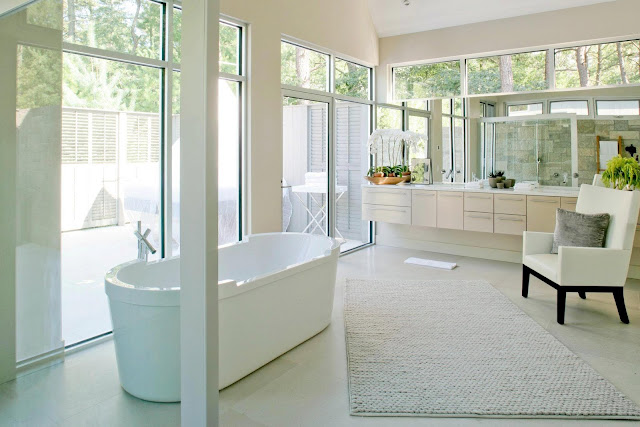 Master bathroom in a modern farmhouse with a stand alone tub, large windows and neutral cabinets