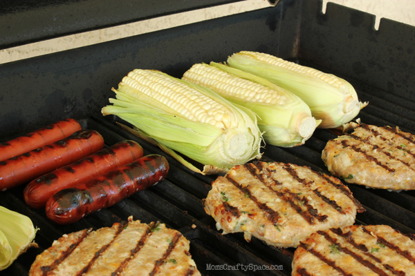 grilling turkey burgers with corn and hot dogs