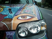 headlight of car with eye painted above it and other bright colors around lamp