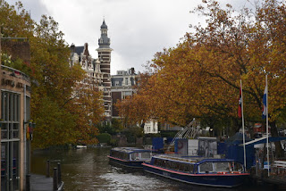 Trees with yellow leaves line a canal with a view of a tower, Amsterdam, The Netherlands