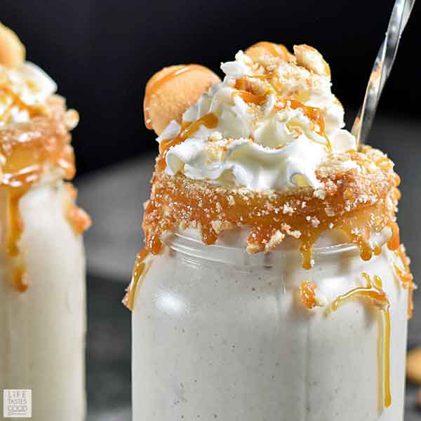Banana Pudding Milkshake in a glass with caramel and cookies around the rim