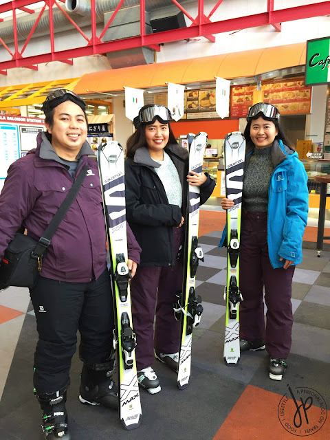 three people wearing ski wear and carrying skis