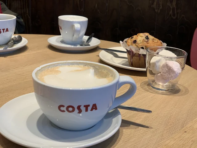 A table in Costa with a number of mugs and Blueberry Muffin on