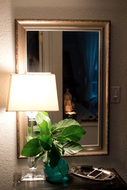 Entryway vignette using a lamp, vase, and mirror.