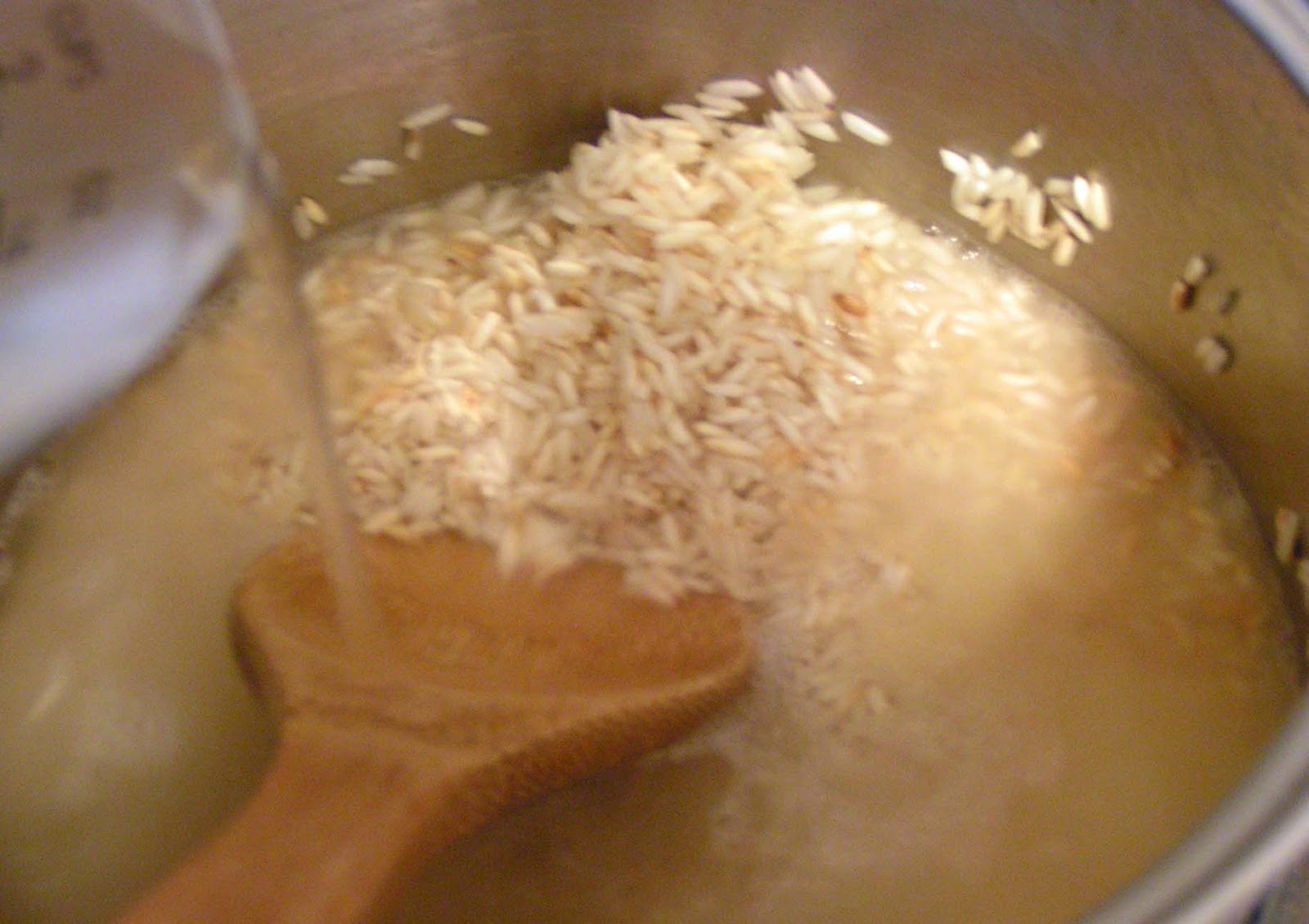 Water being poured into toasted rice in a hot saucepan.
