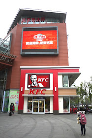girl looking a video display above a KFC