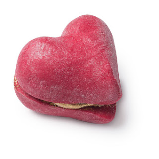 Two bright red heart shaped bubble bars sandwiched between a gitter covered bright gold heart shaped cream on a white backgroubnd.