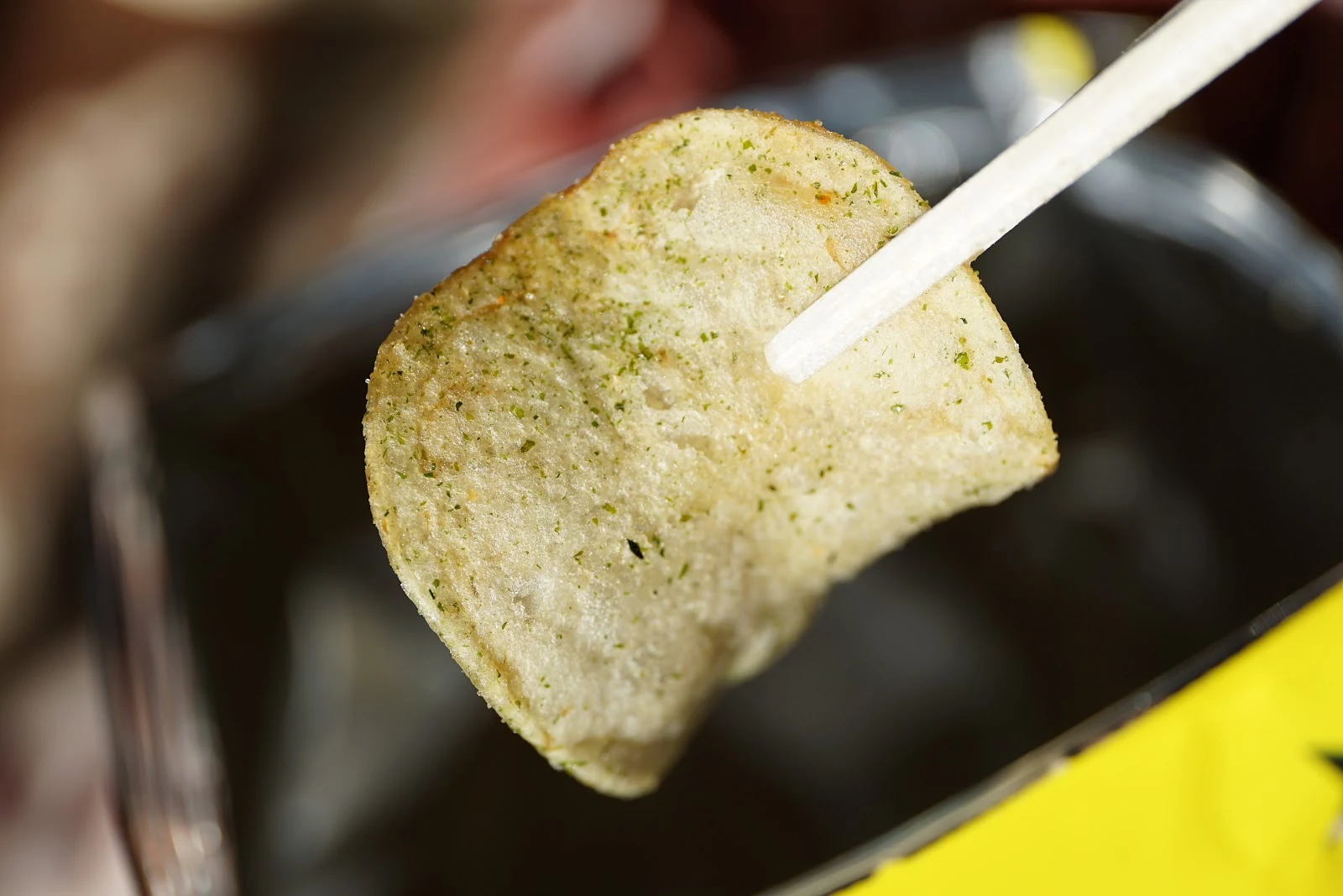 袋からのり塩のポテトチップスの一枚を箸で持ち上げている