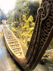 One-twelfth-scale diorama of a maori waka (war canoe) at the edge of a river.