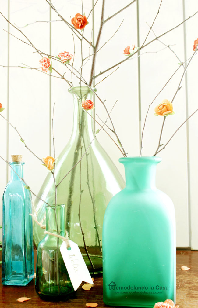 green and blue vases filled with branches with paper blossoms