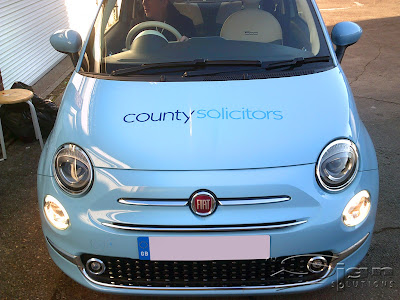 The front of County Solicitors car with the logo on the bonnet of the Fiat 500 in baby blue.