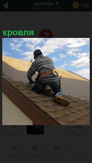 Мужчина на крыше производит ремонт кровли дома инструментом