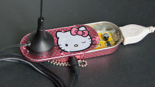 [Image: Photo of a very small radio hotglued inside a Hello Kitty branded tin.]