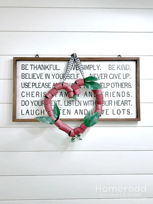 Red TP wreath hanging on a sign with shiplap wall