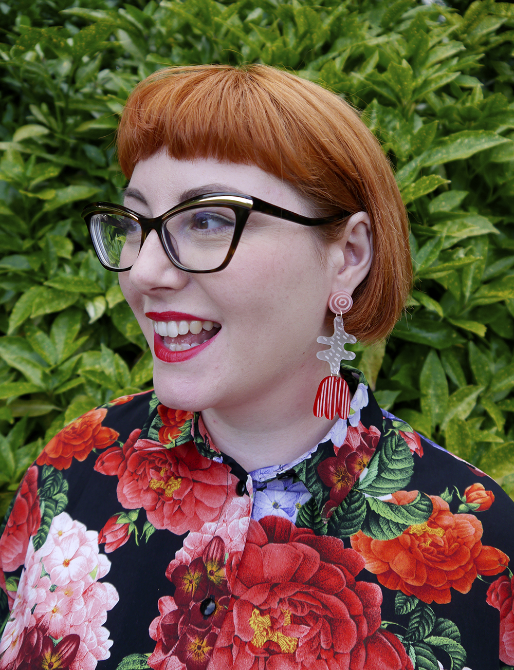 Portrait of red headed bloger with glasses and floral earrings