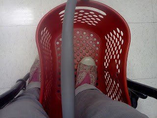 a picture of my feet while using my wheelchair, Target shopping basket propped on the footplate, one foot in the basket