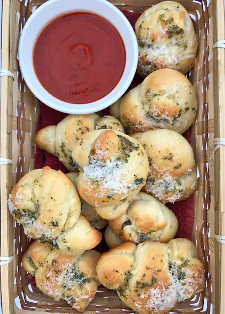 Basket of baked garlic knots with sauce.