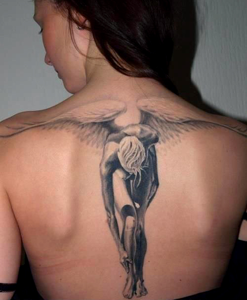 chica morena de espaldas, sonrie mientras nos enseña un tatuaje de angel de la guarda que le cubre la espalda
