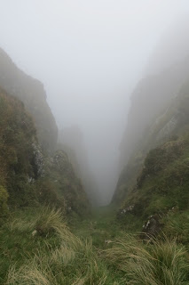 A cleft in crags, wreathed in mist.