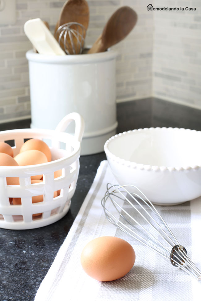 brown eggs in basket with whisk and wooden spoons - kitchen counter
