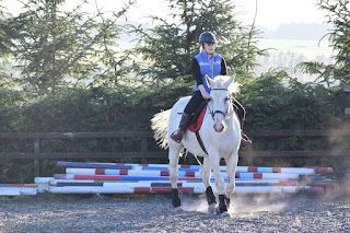 Big white horse being ridden in a outdoor riding school