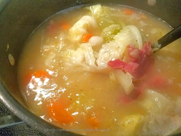 this is a soup pot boiling with cabbage, potatoes, ham and carrots made into a rich broth.