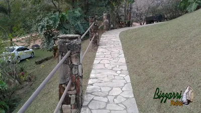 Caminhos com pedras caco de São Tomé com o corrimão de ferro preso nos pilares de pedra em sítio em Atibaia-SP.