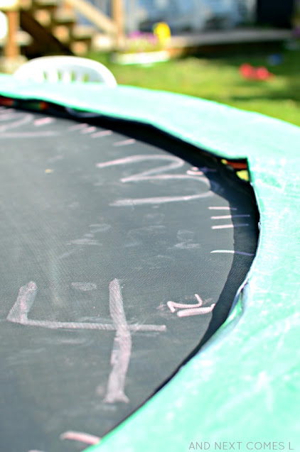 Close up of sidewalk chalk clock on a trampoline as part of a telling the time activity for kids