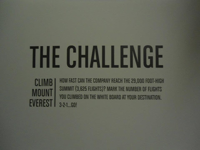 Image of a sign on the wall inside the Reebok Headquarters, that reads "The challenge: how fast can the company reach the 29,000 foot  high summit (3,625 flights?)