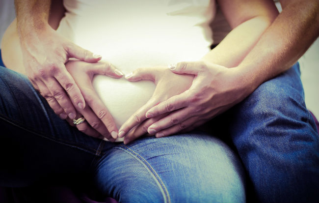 Donna incinta e il suo uomo con le mani sul pancione