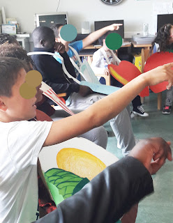 Alunos sentados apontam com as mãos para participar numa atividade