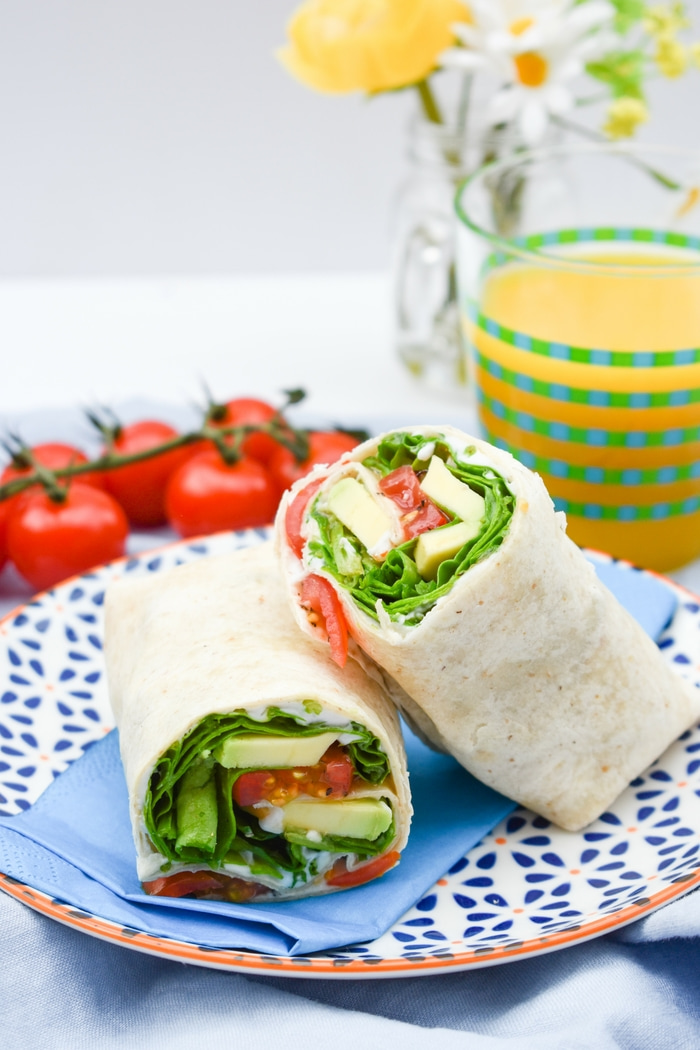Green power lunch wrap (with spinach, tomato and avocado) serve with an apple and orange juice