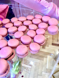 A large oval metal silver plate containing lots of little pink Macarons filled with pink buttercream on a bright background. 